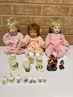 Three porcelain dolls and assorted small collectibles overview