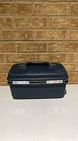 Front and top exterior of dark blue Samsonite train case with handle and latch strip