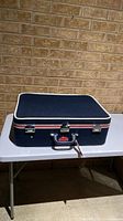 Closed navy blue Skyway suitcase on table showing exterior, latches, handle, wheels not visible