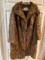 Full front view of brown mink fur coat hanging on door, showing overall style and length