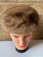 Front view of light brown mink fur hat displayed on mannequin head