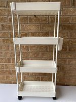 Front angled view of white plastic 4-tier rolling cart with side cup and wheels
