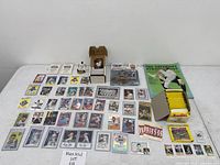 Wide view showing assorted loose cards, card storage box with Barry Bonds card, two sticker packs, two figurines, Starting Lineup figure, vintage magazine, and sealed card pack box
