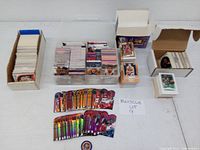 Full view of the basketball card collection across multiple containers including cardboard boxes and a plastic bin holding various cards and separate holographic card stacks.