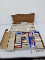 Four open cardboard boxes filled tightly with basketball cards organized in rows, showing edges and some card fronts and backs.