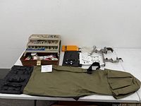 Wide view of the fishing tackle box, rod holder bag, clamps, and other accessories laid out on a table.