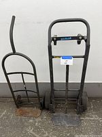 Pair of hand truck dollies against white wall, showing overall appearance and tire types.