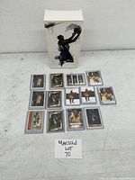 Front view of the Kobe Bryant action figure box with basketball cards laid out in front.