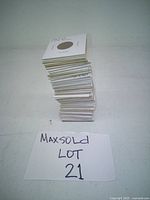 Stack of 38 Lincoln wheat pennies in white protective coin sleeves with staples, upright on a plain surface.