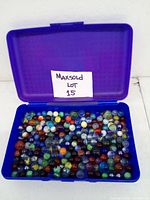 Blue plastic box open to reveal over 50 assorted colorful glass marbles of various sizes and designs.
