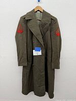 Full front view of vintage olive drab military coat hanging on a hanger