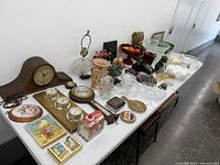 Overview of lot arranged on table showing bowls, dishes, collectibles, figurines, toys, and electronics