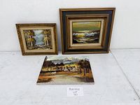 Three framed original oil paintings on canvas placed against white wall, showing different landscape scenes.