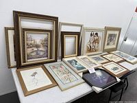 Overview of various framed artwork and empty frames on a table