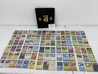 90 holographic Pokémon cards laid out with black binder behind