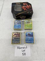 Lot includes four stacks of Pokémon cards and a Pokémon tin storage container
