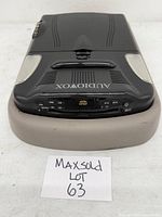 Full view of the Audiovox portable DVD player placed on a grey padded support with visible control panel and brand name.