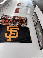 Photos of two San Francisco Giants baseball banners and three framed photos arranged on the floor and against a wall.