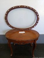 Vintage wooden oval coffee table with carved legs and decorative apron, warm wood tone finish.