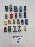 Photo showing 21 vintage metal cars and trucks assorted models, from front view on a white surface with a Maxsold lot label.