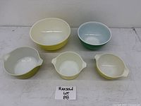 Top view of five vintage Pyrex bowls in different colors and sizes on table.