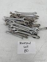 Overhead view of the full assortment of wrenches showing mixed sizes and both box and open-ended types scattered on a white surface with a label "MAXSOLD LOT 80".