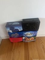 Six colorful themed Pokemon card boxes standing upright against a wall, showing artwork and expansion logos such as Silver Tempest and others