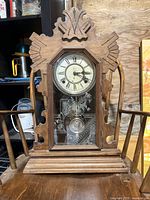 Front full view of the antique carved wood mantel clock showing its ornate crown and etched glass door.