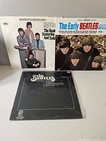 Three Beatles vinyl LP covers including 'Yesterday and Today', 'The Early Beatles', and '1st Live Recordings' album with records partially visible.