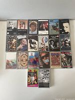 Cassette tapes arranged facing up to display the album art and artist names, showing variety and condition of case and cover graphics.