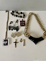 Full view of various costume jewelry pieces arranged on white surface including necklaces, earrings, pendants, and charms