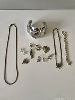 Full lot laid on white surface showing multiple jewelry pieces including cuff bracelet, necklaces, bracelet, earrings, and many small charms