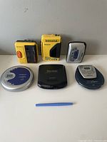 All six devices displayed on a white surface with a small blue tool for scale.