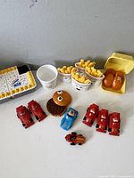 Photo showing variety of McDonald's toys including fries containers, hamburger toy, cars with Ronald McDonald figures, and egg carton with characters.