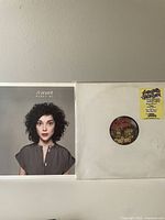 Photo of cover sleeves for St Vincent's 'Marry Me' and Lucious Jackson's 'Deep Shag' vinyl records side by side on white wall.