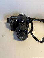 Front-left side view of Nikon D50 DSLR camera with lens and strap, showing the lens cap and Nikon branding.