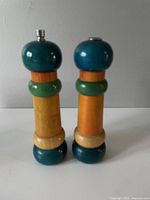 Front view of two wooden salt and pepper shakers with distinct multicolor segments showing teal, green, orange, and natural wood finishes.