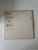 Front cover of vinyl album showing the iconic white brick wall design with handwritten title 'Pink Floyd The Wall'.