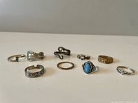 Photo of nine assorted rings arranged in two rows on white background