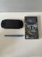 Front view of black Sony PSP console, Star Wars Force Unleashed game case, and pen for size reference