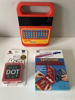 Front view of Speak & Spell, On the Dot game, and Travel Battleship box showing logos and condition