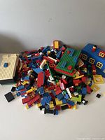Wide view showing pile of multicolor Lego bricks with some partially built structures and base plates