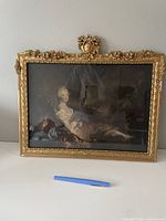 Full frontal photo of vintage portrait in gilded gold-colored decorative frame resting on a white surface, with visible reflections on glass.