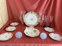 Photo showing assorted hand painted china plates and bowl with floral patterns and two glass hurricane lamps along with two small stemmed glasses