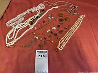 Lot overview with pearl necklaces, chain, earrings, and pendants spread on red fabric
