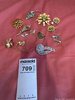 All brooches and clip earrings arranged on a cloth, showing variety of designs and sizes.