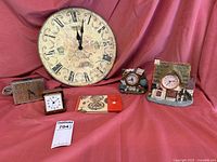 Full lot of five decorative clocks arranged on pink fabric background.