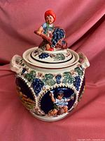 Full view of the German soup tureen with the lid on, showing the finely painted grapevine and castle relief designs and the figure on the lid.