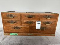 Front view of large wooden jewelry box with eight drawers and brass handles.
