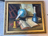 Framed still life oil painting depicting nautical and scholarly items including globe, candle, book, quill, and scroll with visible signature.